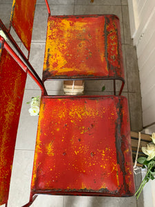 Pair of red/orange metal stacking chairs