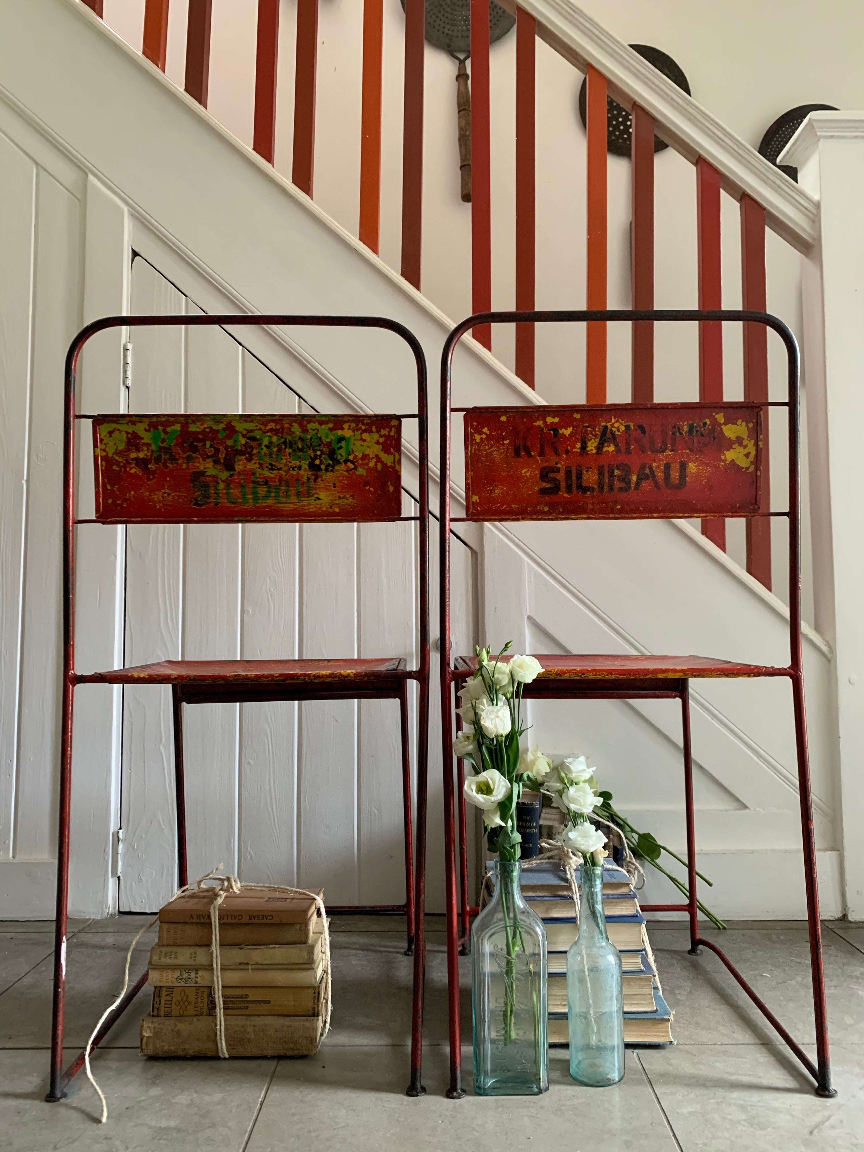 Pair of red/orange metal stacking chairs