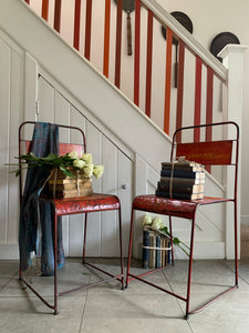 Pair of red/orange metal stacking chairs